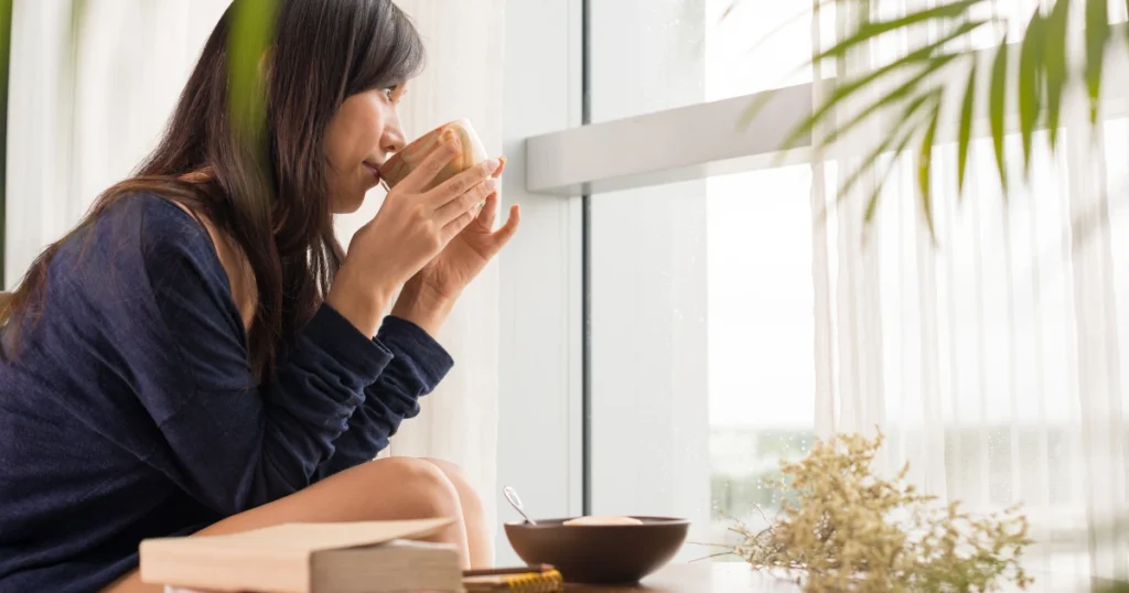 A woman reflecting at her desk with a notebook and calculator — visualizing advice for paying off credit card debt with less stress.